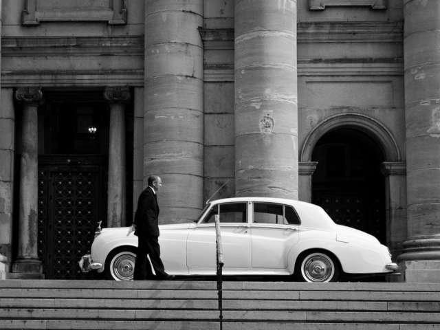 A chauffeur waiting next to his car.